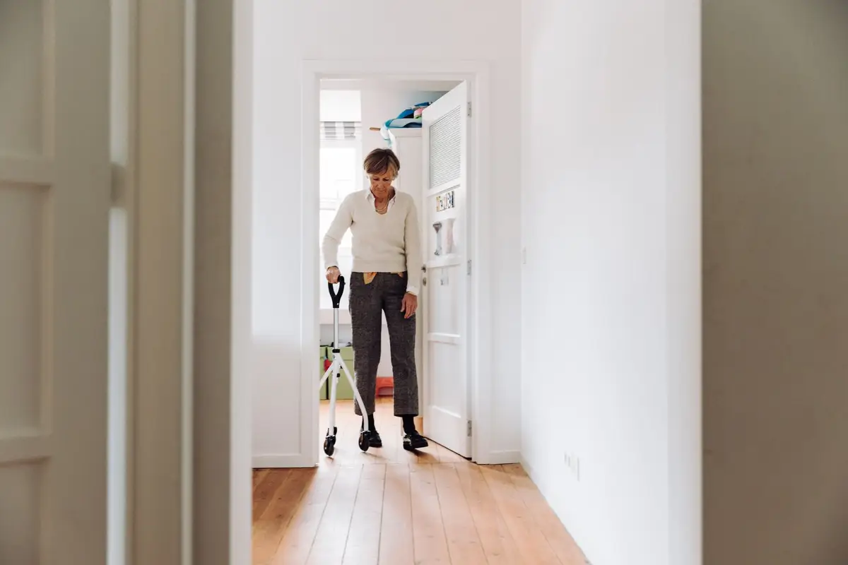 Older woman walking with a rollator in a bright hallway (Who should not use a jetted walk-in tub? The cautions, with their sources)